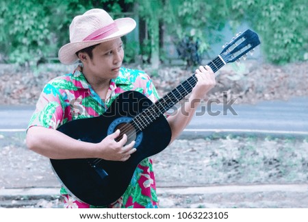 Handsome Asian male playing acoustic guitar at relax time ,with summer clothes abstract summer,relax background 