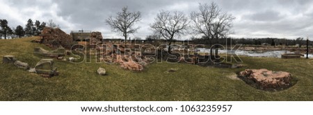 The Big Sioux River flows over rocks in Sioux Falls South Dakota with views of wildlife, ruins, park paths, train track bridge, trees and city in the surrounding area and background
