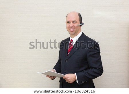 Business man with a handsfree telephone headset holding a document.