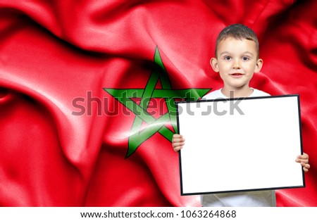 Cute small boy holding emtpy sign in front of flag of Morocco
