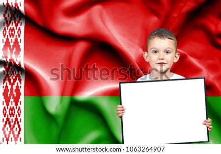 Cute small boy holding emtpy sign in front of flag of Belarus
