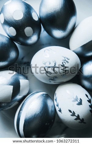 Group of diverse silver Easter eggs in a marble plate  on black background, original stylish idea, selective focus