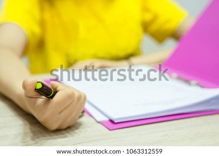 Female hands holding pen, writing. Side view on woman on trendy color pink desk. Woman and stilish workplace. Cup of coffee, phone, notebook. Breakfast, phone, coffee. Women's Day concept