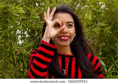 Young latin woman celebrating success with an okay sign in the park