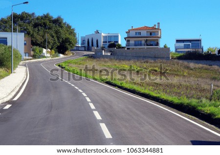 An asphalt road with a marking in the countryside. Houses on the hills. Empty street.