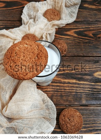 milk in a small bottle with oatmeal cookies and cones on a wooden table and beige runner