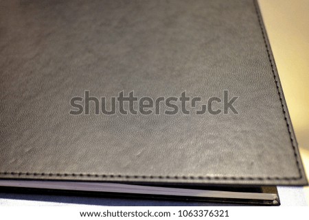 In selective a leather cover black book on the wooden table with soft night night for background texture 