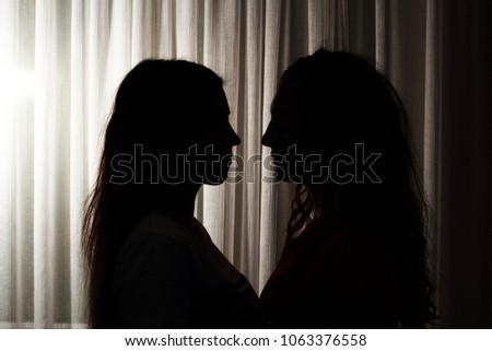 Two loving girls are looking at each other, happy couple of LGBT people, silhouettes on a light background