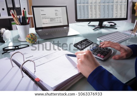 Close-up Of A Businessperson's Hand Calculating Invoice At Workplace Royalty-Free Stock Photo #1063376933