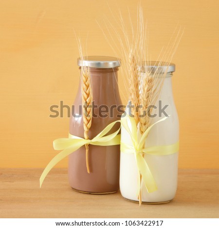image of milk and Chocolate with wheat over wooden table and pastel background. Symbols of jewish holiday - Shavuot