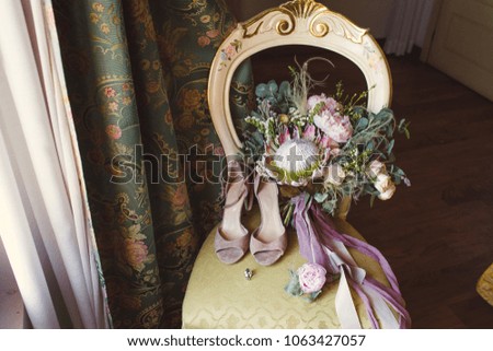 A beautiful wedding bouquet of ribbons, shoes and wedding rings on a chair.