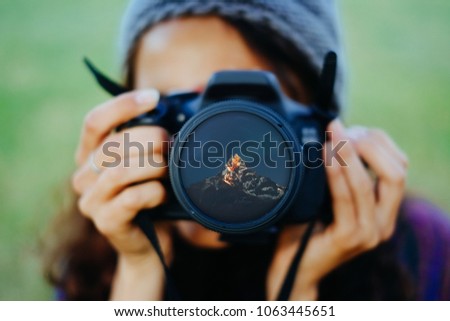 Young woman holding a camera with Himalayas mountains reflect in a front lens