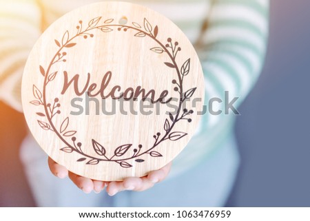 WELCOME CONCEPT.Women holding welcome word wooden board at home.