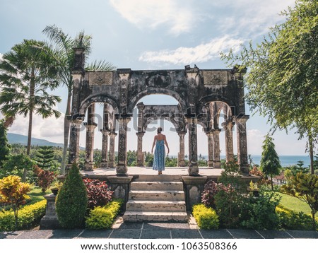 Young woman in dress in Water Palace Soekasada Taman Ujung Ruins on Bali Island in Indonesia. Amazing old architecture. Travel and holidays background. Royalty-Free Stock Photo #1063508366