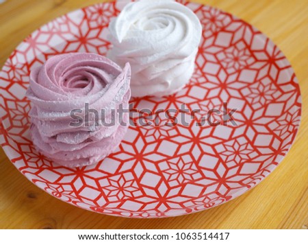 Fresh homemade berry marshmallow on red decorated plate on wooden background. Sweet zephir for happy birthday.