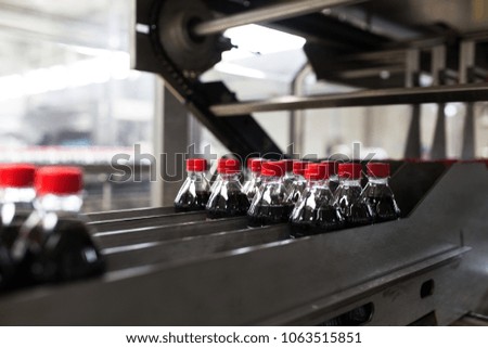 Bottling factory - Black juice or soft drink bottling line for processing and bottling juice into bottles. Selective focus. 