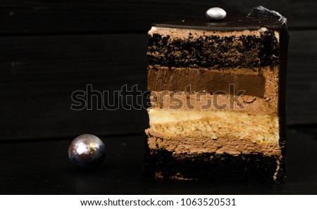 Delicious multi-layered chocolate cake on a black background with silver decorate balls 