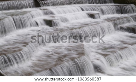 Water Cascading over Weir Step in river canal showing white water sharp and blurry