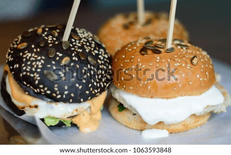 Hamburgers of different colors, sprinkled with pumpkin seeds, close-up