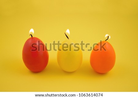 Egg candle stock images. Colored candles on a yellow background. Easter concept