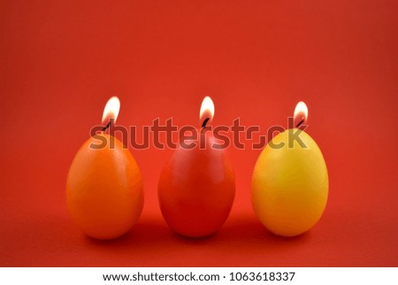 Egg candle stock images. Colored candles on a red background. Colorful Easter candles. Easter concept