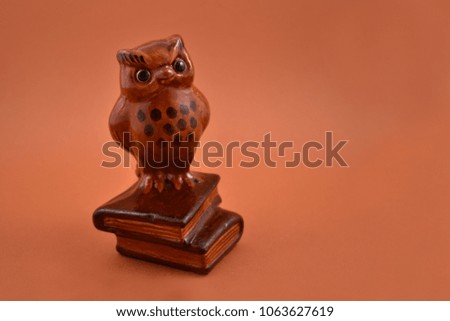 Wise owl figurine stock images. Owl figurine on a brown background. Brown owl on a pile of books