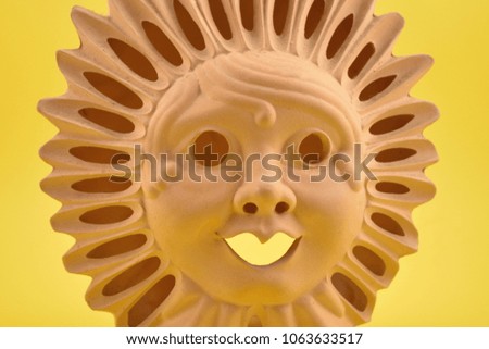 Ceramic Sun Face stock images. Ceramic sun on a yellow background. Sun decoration. Sun clay lamp