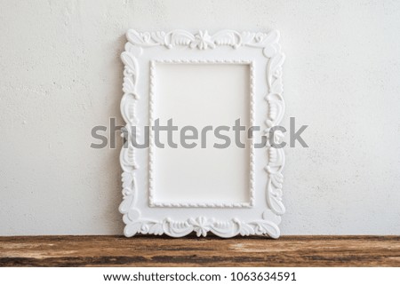 White vintage photo frame on old wooden table over white wall background