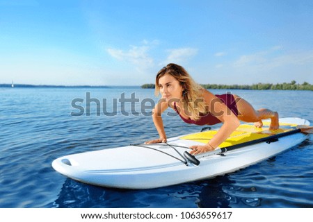 Sportive woman making push-ups on the sup board