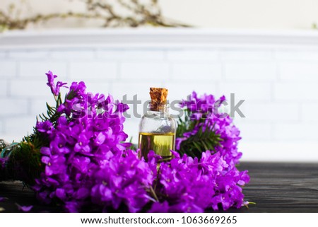 Oil bottle. Small aromatics bottle. Perfume bottle. The beautiful lilac on a wooden background. Macro image of spring lilac violet flowers, abstract soft floral background