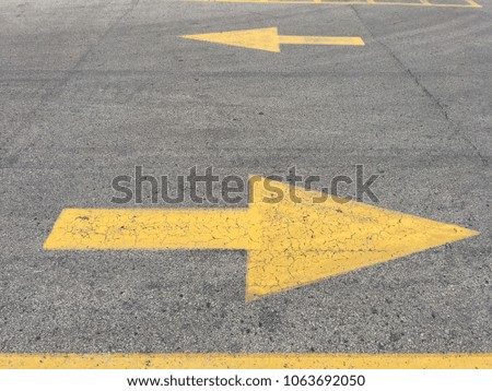 Painted yellow directional arrows on asphalt parking lot surface