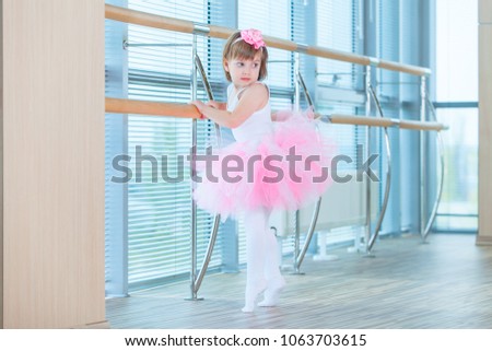 Little ballerina girl in a pink tutu. Adorable child dancing classical ballet in a white studio. Children dance. Kids performing. Young gifted dancer in a class. Preschool kid taking art lessons.