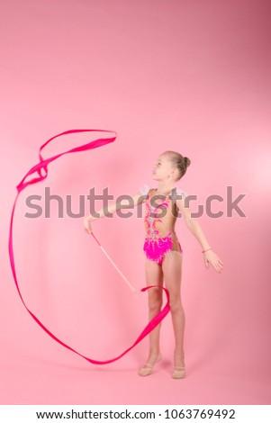 Cute yong girl doing gymnastic exercises on pink background. 