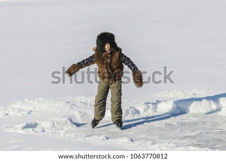 boy skates in cold white winter on frozen lake
