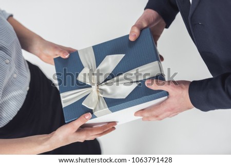 Cropped image of couple in office clothes holding a gift box, isolated on white