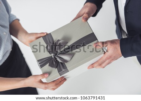 Cropped image of couple in office clothes holding a gift box, isolated on white