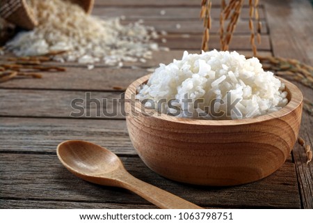 Jasmine rice in wood bowl and paddy rice on a brown wooden background beautiful Thai food Royalty-Free Stock Photo #1063798751