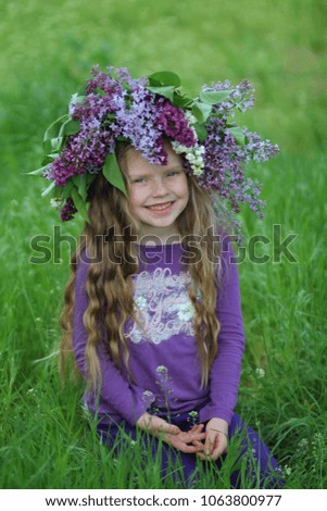Little girl wearing a lilac wreath, green grass background, spring, flowers
