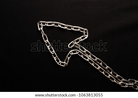Arrow pointing upwards from a metal chain on a black background, links of one chain