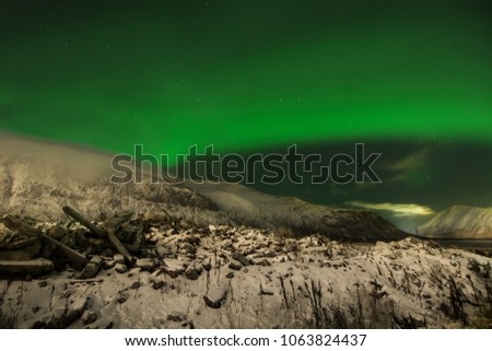 Northern Lights - Aurora borealis over mountains. Beautiful picture of massive green vibrant Polaris in the night sky above of Scandinavia during a geomagnetic storm. Garbage dump. Soil pollution.