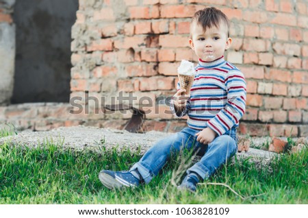little cute boy eating ice cream three years very appetizing, amid nature, green grass
