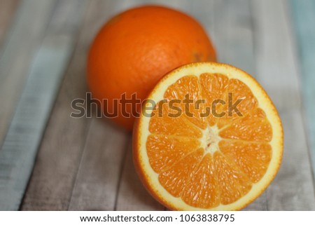 Close up picture of orange cut in half next to one whole orange. 
