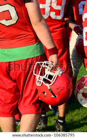 rugby players, side view rugby or American football players holding red helmets. American football team sport concept photo. sport background or surface with players in red helmet and uniforms