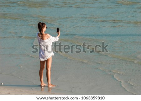 Lovely European girl using mobile phone selfie while walking  on the beach