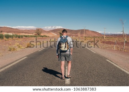 Hipster on the road through the desert