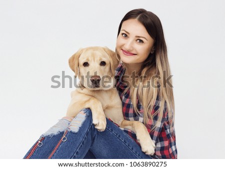 girl hugging a dog labrador on a gray background