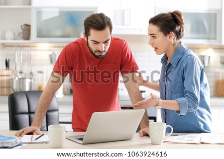 Young couple having argument about family budget in kitchen Royalty-Free Stock Photo #1063924616