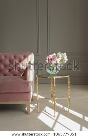 A large beautiful pink sofa stands in a spacious living room in a classic style. Interior with vintage furniture elements.