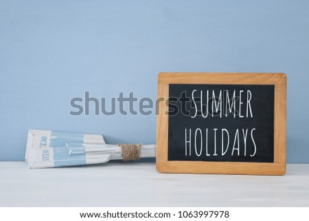 nautical concept with wooden decorative boat oars and blackboard over blue background