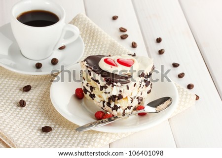 sweet cake with chocolate on plate and cup of coffee on wooden table